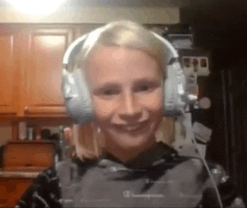 a woman wearing headphones and a champion shirt smiles at the camera