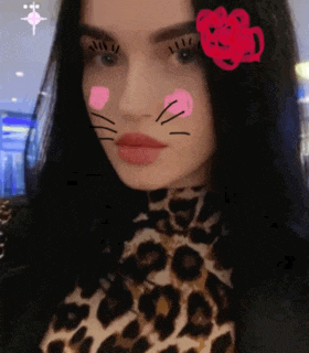 a woman wearing a leopard print shirt has a cat face on her face