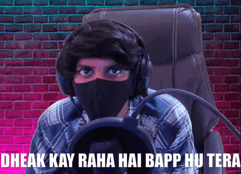 a man wearing headphones and a mask says " dhaak kay raha hai bapp hu tera " in front of a microphone