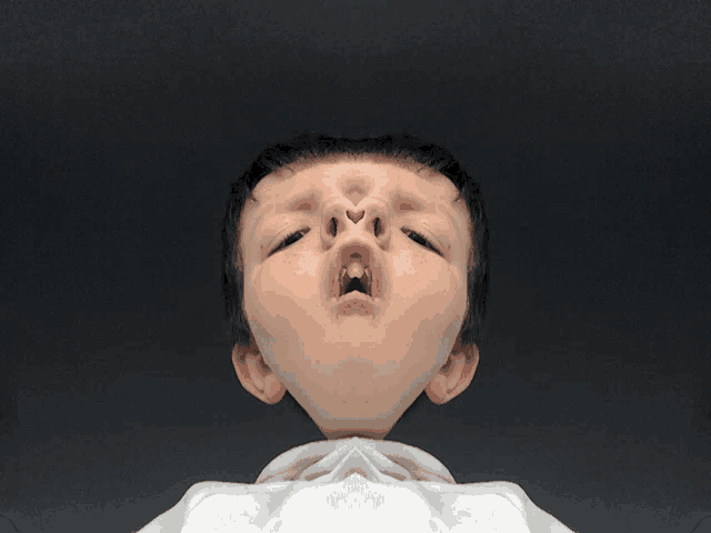 a close up of a child 's face with a white shirt around his neck