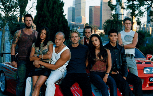 a group of people are posing for a picture with a red car in the background