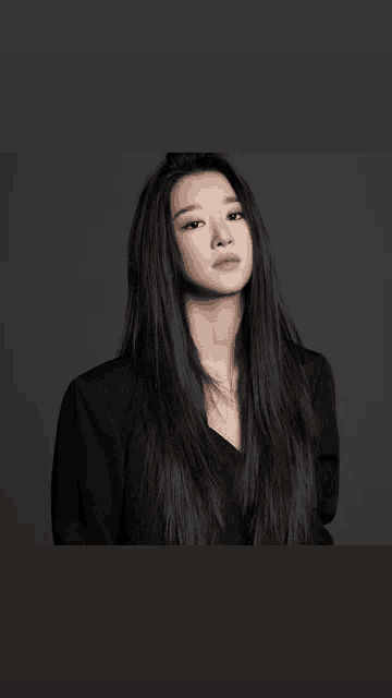 a woman with long black hair is standing in front of a black background