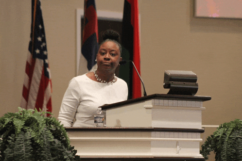 a woman stands at a podium with a bottle of aquafina water on it