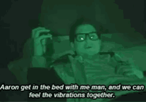 a man wearing glasses is laying in bed with a cigarette in his hand and a quote .