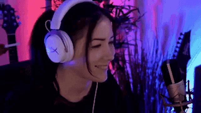 a woman wearing headphones and a microphone is sitting in front of a guitar .