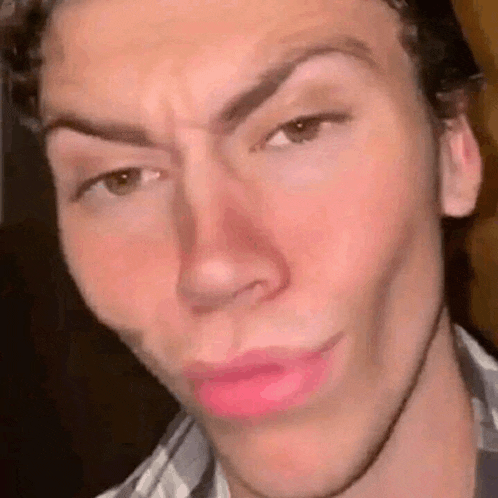 a close up of a man 's face with pink lipstick on his lips making a funny face .