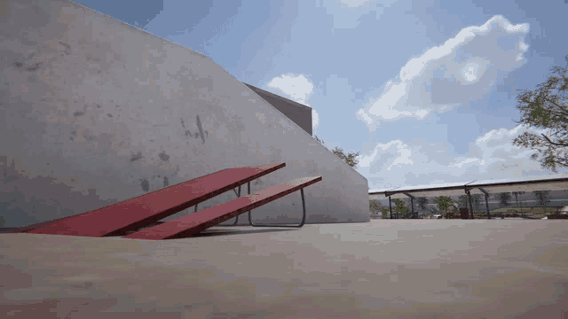 a red picnic table is sitting in front of a wall