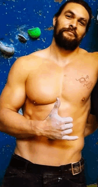 a shirtless man giving a thumbs up with a tattoo on his chest that says om