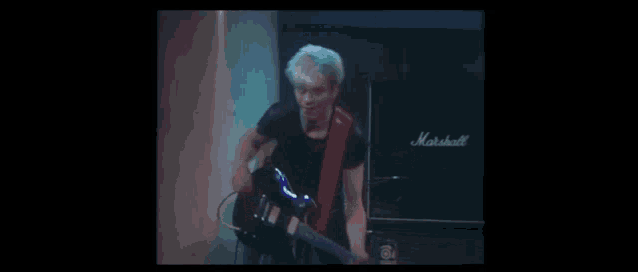 a man is playing an electric guitar in front of a marshall amp .