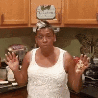 a woman in a white tank top is standing in a kitchen with a sign above her head that says kitchen .