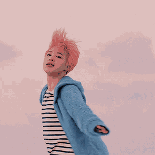 a young man with pink hair is wearing a striped shirt and a blue sweater