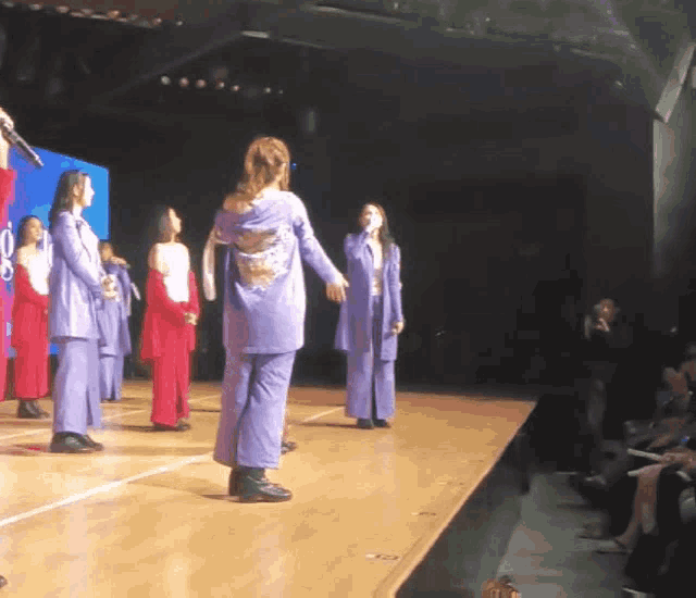 a group of women are standing on a stage in front of a blue screen that says ' o ' on it