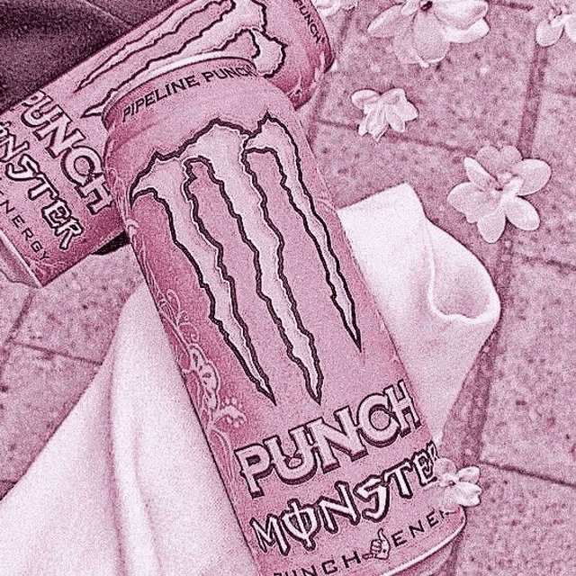 a pink monster energy drink is sitting on top of a white towel on a table .