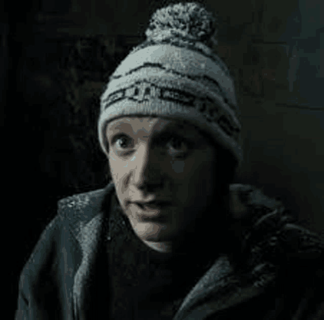 a man is wearing a knitted hat and a jacket .