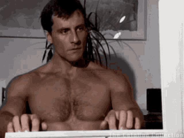 a shirtless man is typing on a laptop computer ..