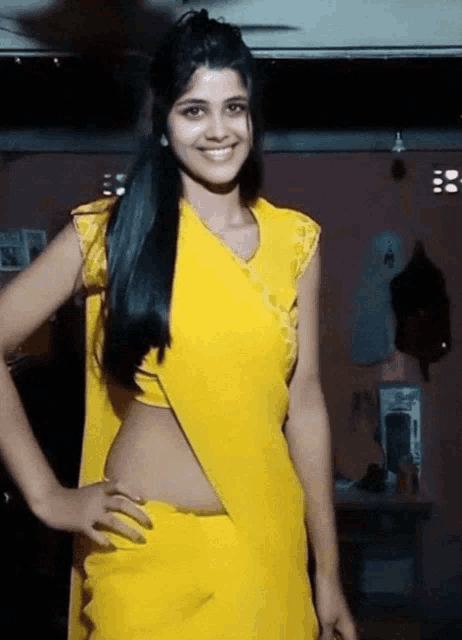 a woman wearing a yellow top and a yellow saree stands with her hands on her hips