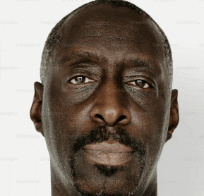 a man with a beard looks at the camera with a white background behind him
