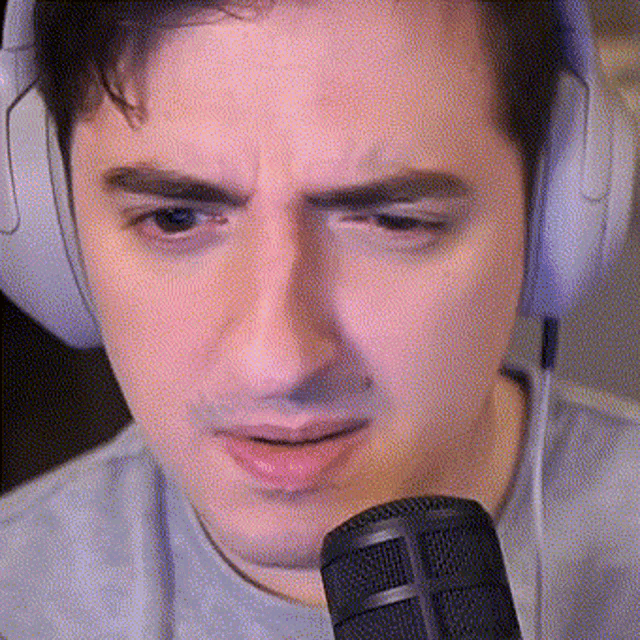 a man wearing headphones is talking into a microphone and making a funny face .