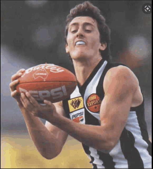 a man in a black and white jersey holds a pepsi football