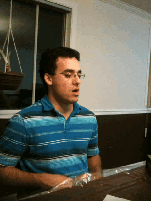 a young man wearing glasses and a blue striped shirt