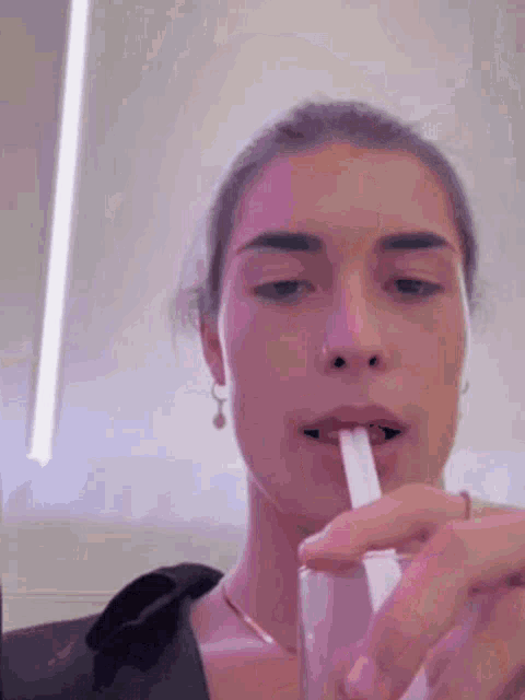 a woman is drinking through a straw out of a glass .