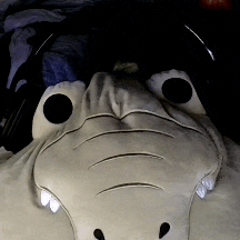 a stuffed animal that looks like a crocodile has headphones on it