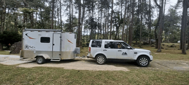 a white land rover is parked next to a white trailer