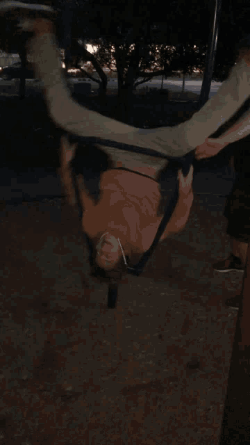 a person hanging upside down on a swing set