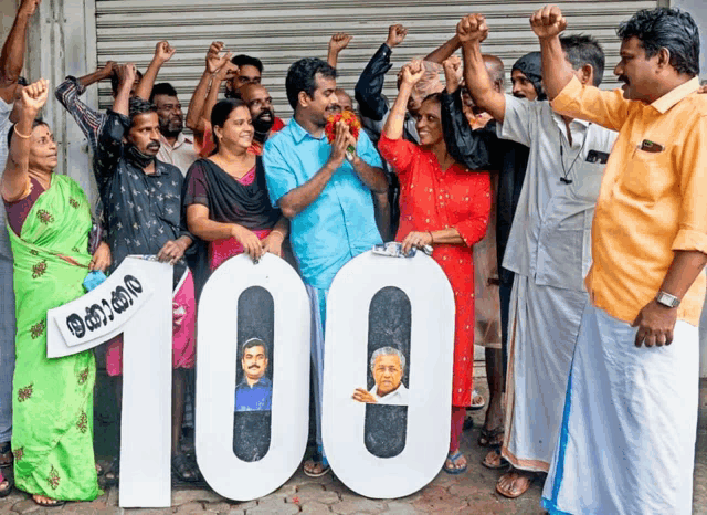 a group of people holding up their fists in front of a sign that reads 100