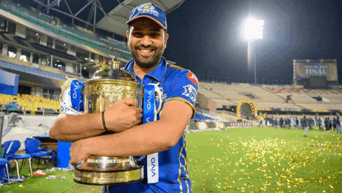 a man in a blue shirt is holding a trophy in his hands .