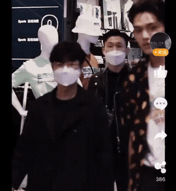 a group of young men wearing face masks are standing in front of mannequins in a store .