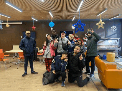 a group of people are posing for a picture in a room with christmas decorations hanging from the ceiling .