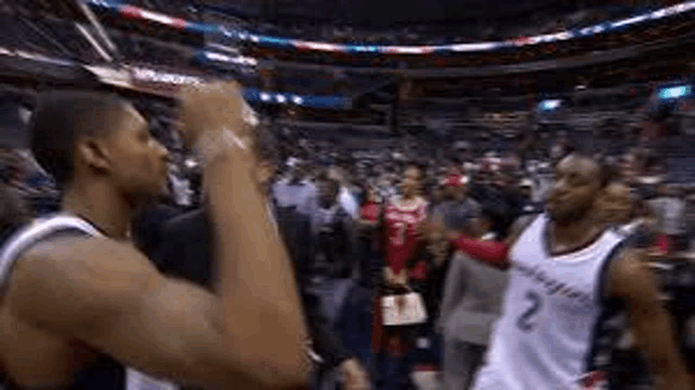 a couple of basketball players are standing next to each other in a stadium .