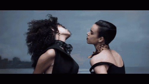 two women are standing next to each other and looking at each other . one of the women has a scarf around her neck .