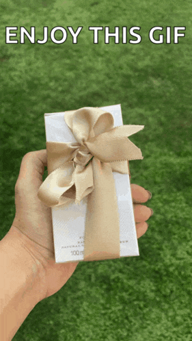 a person holding a gift box with a bow and the words enjoy this gif above it