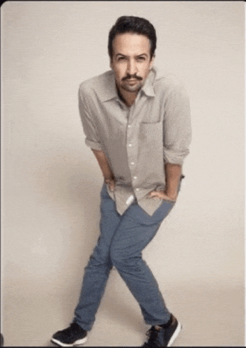 a man with a mustache wearing a grey shirt and blue jeans