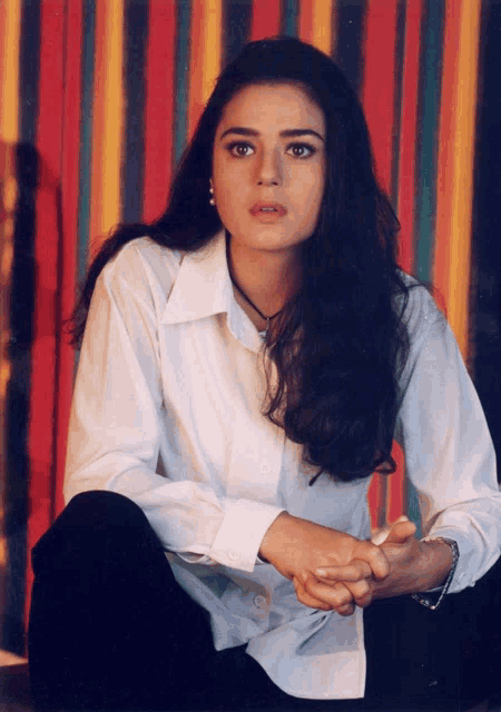 a woman in a white shirt and black pants sits on the floor