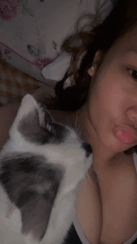 a woman is laying on a bed with a cat on her chest