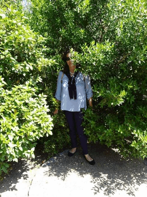 a woman is standing in a bush with lots of leaves