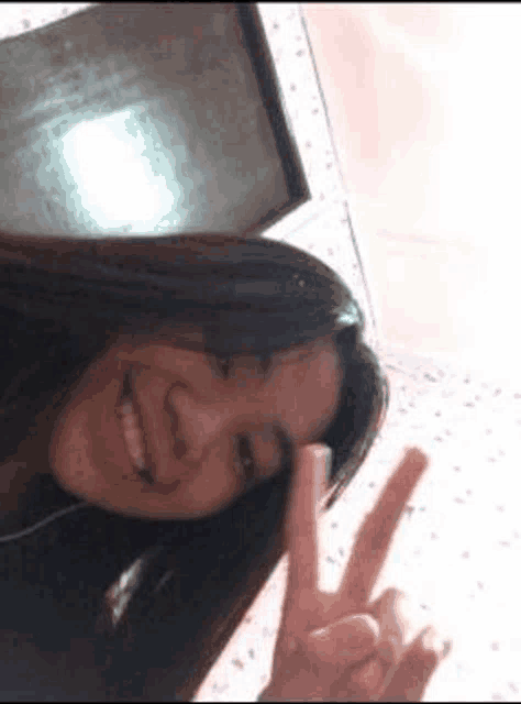 a girl is smiling and making a peace sign with her fingers .