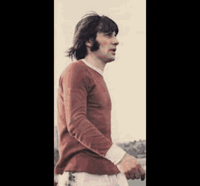 a man with long hair is wearing a red sweater and white shorts .