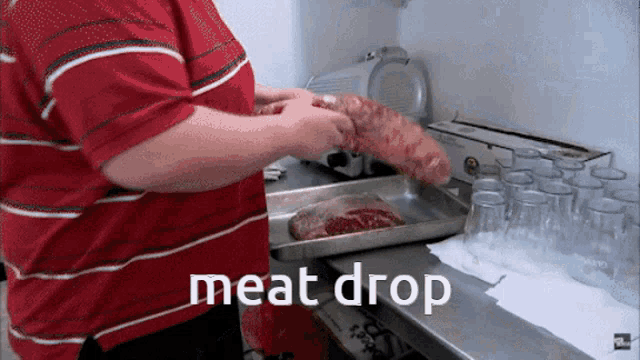 a man in a red striped shirt is holding a large piece of meat in front of a tray that says " meat drop "