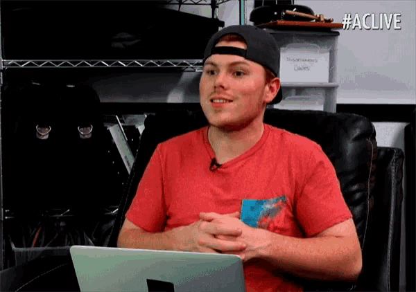a man wearing a hat and a red shirt is sitting in front of a laptop with the hashtag #aclive on the bottom right