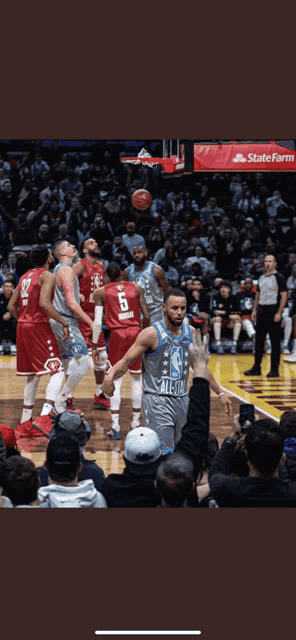 a basketball game is being played in front of a crowd with a state farm ad in the background