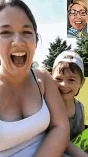 a woman is laughing while holding a child who is wearing a white hat