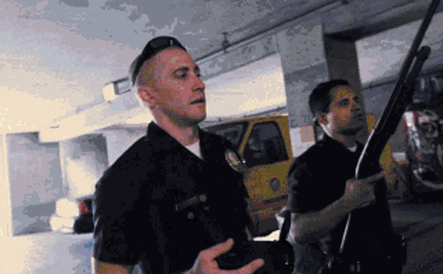 two police officers in a parking garage one holding a shotgun