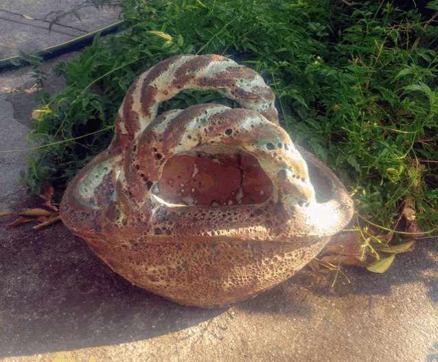 a sculpture of a snake with a handle is sitting on the ground