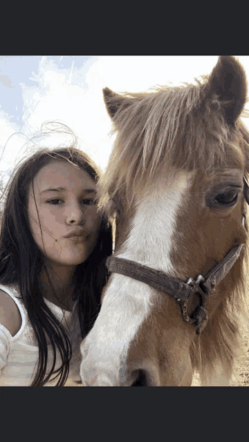 a young girl is standing next to a brown horse