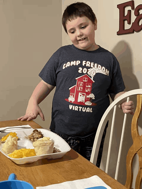 a young boy wearing a camp freedom 2020 virtual shirt