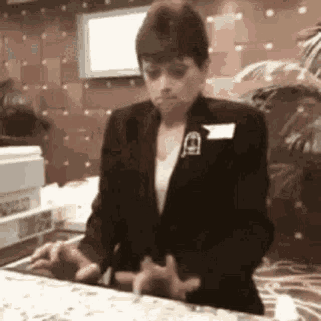 a woman in a black suit is standing at a counter in a restaurant .